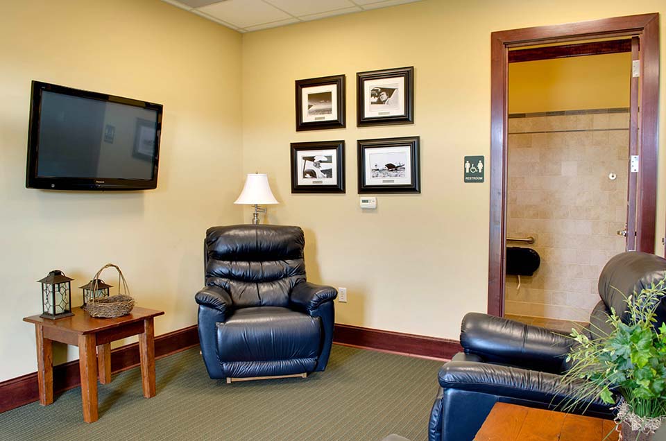 A spacious airport lounge, at the Stanly County Airport. Featuring couches, chairs, book shelfs, a TV, and cozy fireplace.
